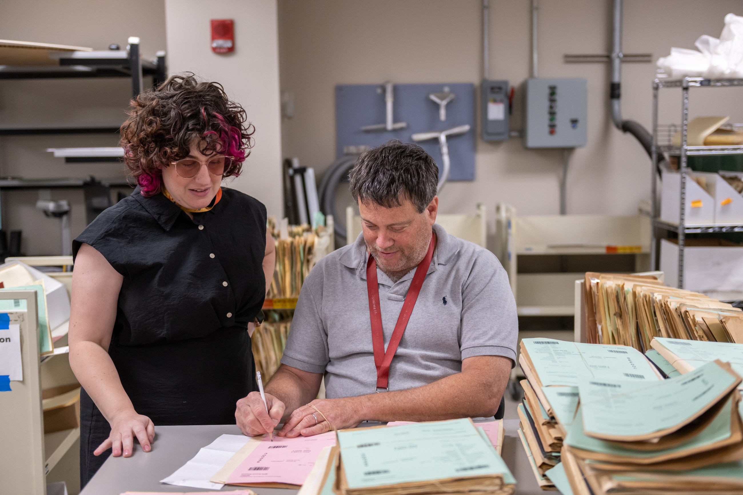 National Archives preservation specialists discuss the condition of a personnel record at the National Personnel Records Center on 2 June 2023.